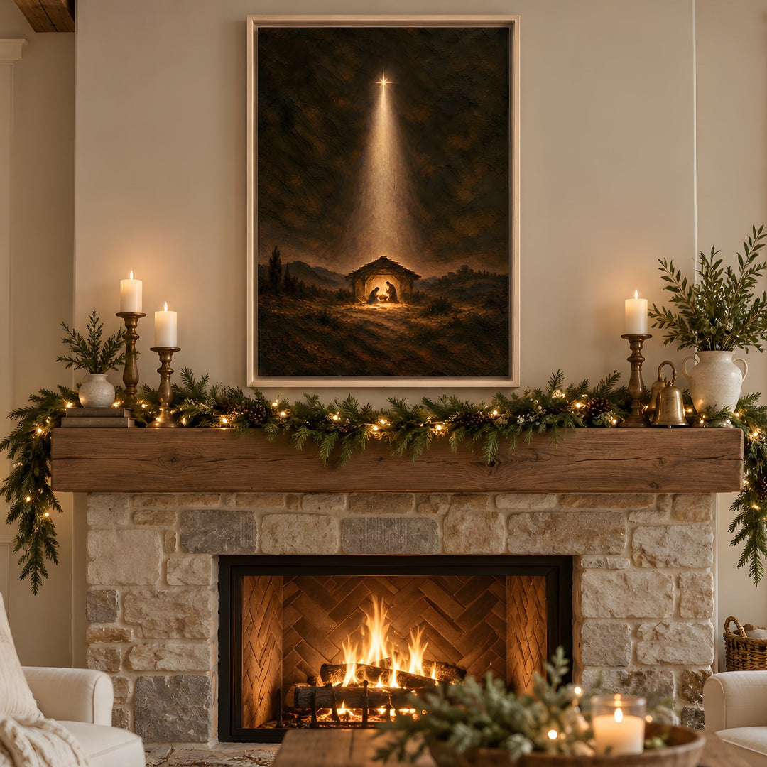 A framed vertical wall art print depicting a Christmas nativity scene with a beam of light, displayed above a stone fireplace in a cozy, decorated living room.