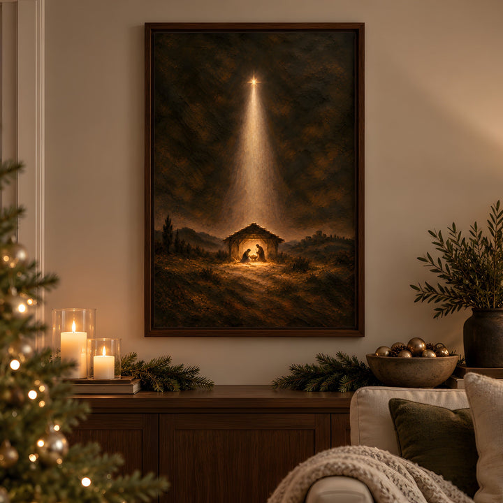 A framed Christmas nativity painting hangs on a warm beige wall in a cozy living room setting, flanked by a lit Christmas tree on the left and a lamp and sofa on the right.