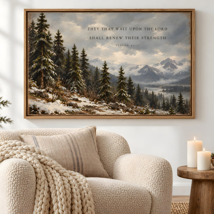 A framed winter landscape art print hangs on a white wall above a cream bouclé armchair in a styled living room. The artwork depicts snow-covered pine trees, distant mountains, and a cloudy sky with the text, 'THEY THAT WAIT UPON THE LORD SHALL RENEW THEIR STRENGTH - SAMUEL II: 15.