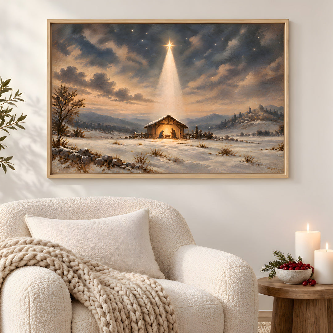 A framed Christmas landscape painting hangs above a stone fireplace in a cozy living room. The painting depicts a snowy winter scene with a small stable under a glowing star in the night sky.