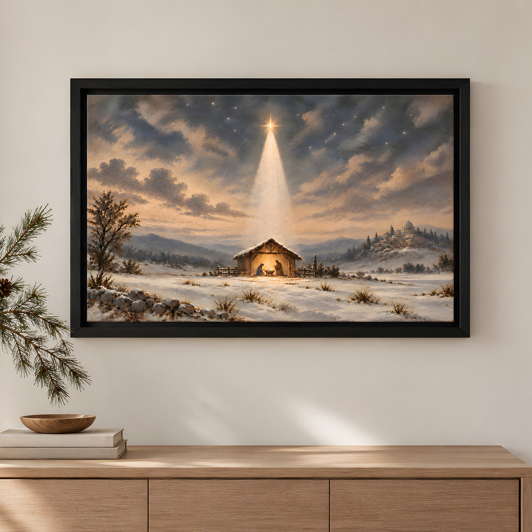 A framed Christmas landscape painting hangs above a stone fireplace in a cozy living room. The painting depicts a snowy winter scene with a small stable under a glowing star in the night sky.