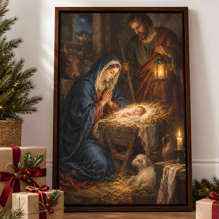 A large framed Christmas nativity painting leaning against a white wall in a decorated room, with wrapped gifts, pine branches, and a small tree nearby. The painting shows Mary in blue, Joseph in red-brown, and baby Jesus in a manger with a sheep.